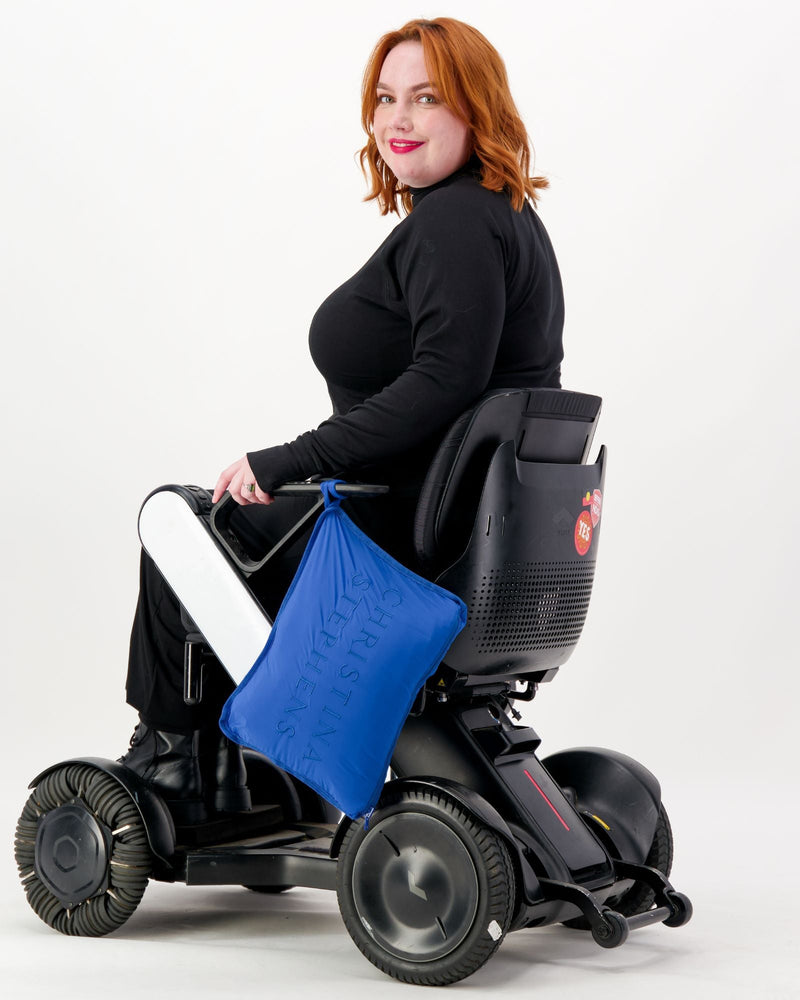 Our seated model with red hair and who is in a wheelchair is wearing a black thermal top with long sleeves, black pants and black boots. Christina Stephens Adaptive Clothing Australia.