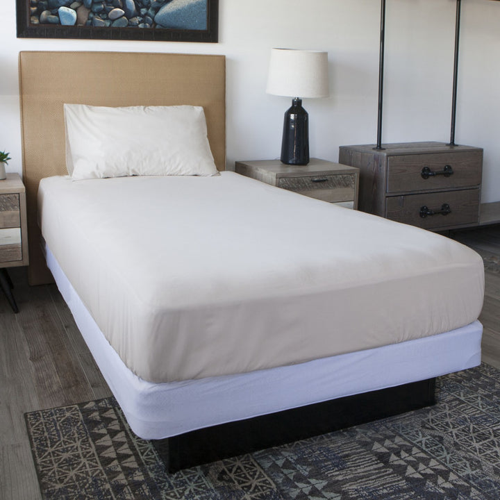 Conni mattress protector in white, showcasing soft fabric and waterproof design for enhanced bed protection.