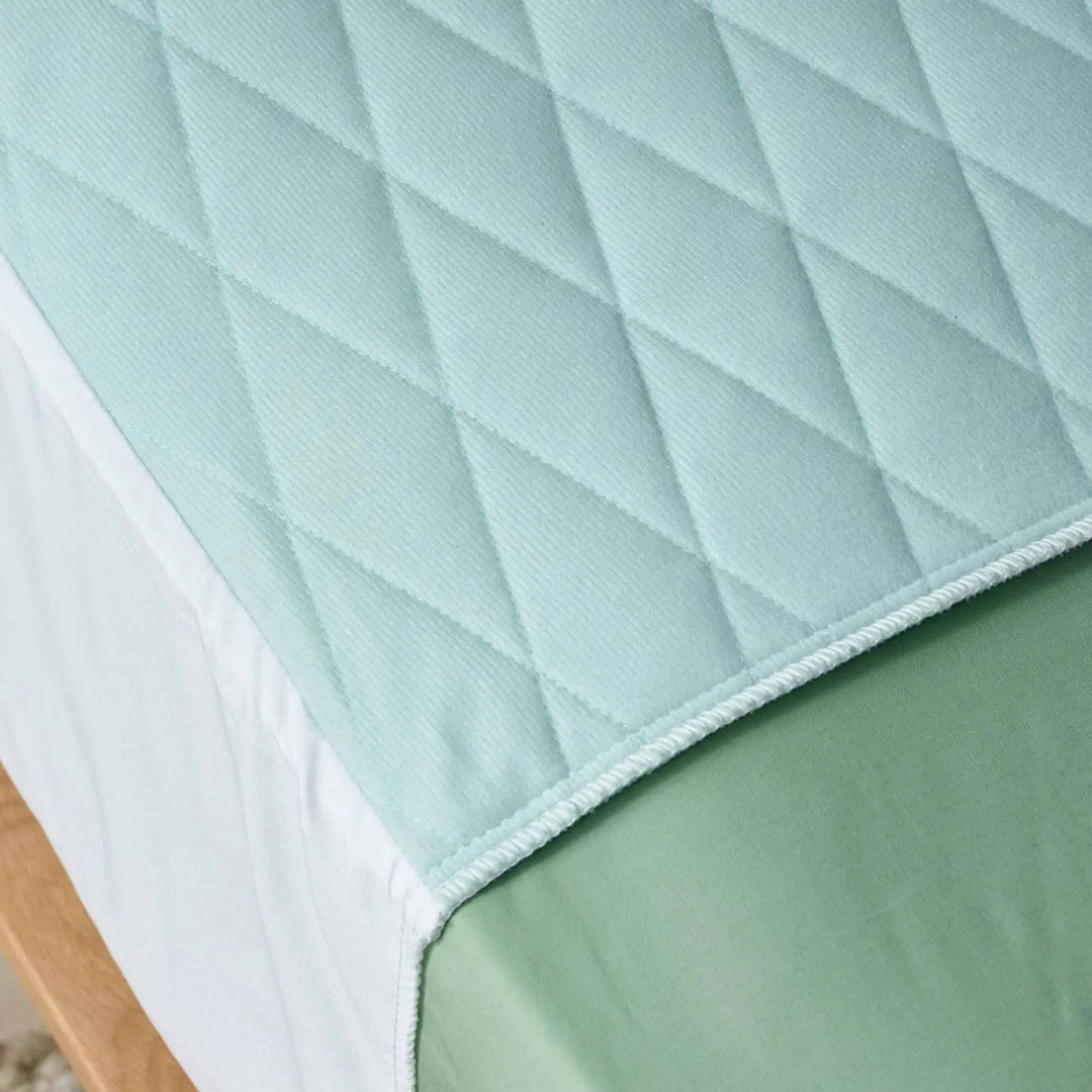 Staydry Forest Check Incontinence Bundle featuring a close-up of a blue bed pad with a checkered pattern.