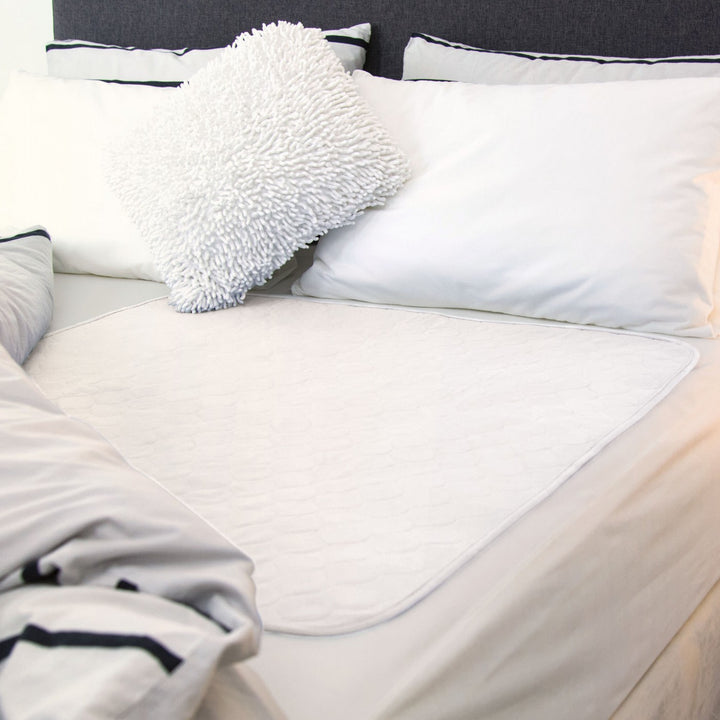 Conni Bed Pad in white, featuring soft fabric and waterproof backing for bed protection and comfort.