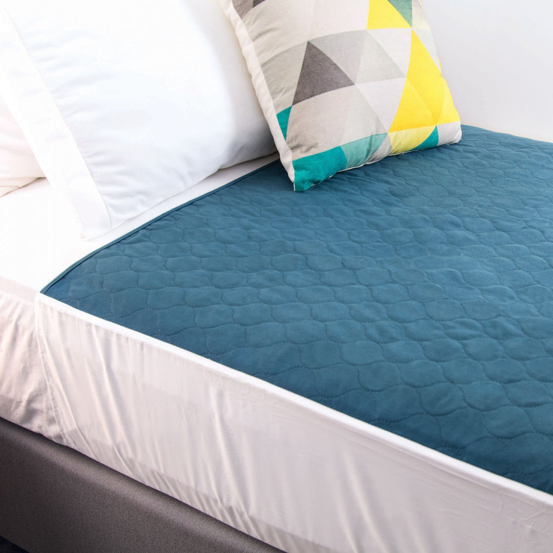 Conni teal Manchester bed pad with tuck-ins, designed for added protection and comfort in bedding.