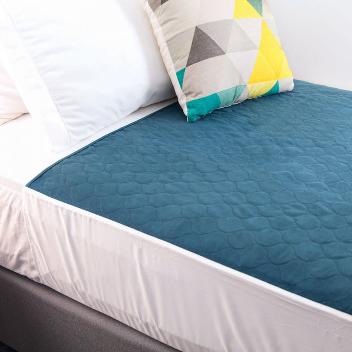 Conni teal Manchester bed pad with tuck-ins, designed for added protection and comfort in bedding.