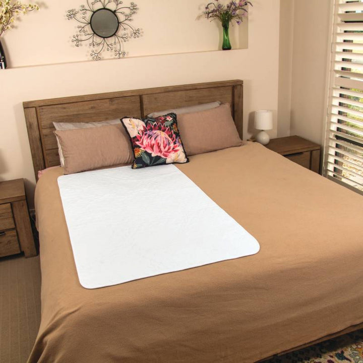 Conni Allrounder Pad in white, featuring absorbent fabric for incontinence protection, displayed on a bed.