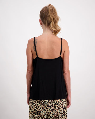 Blonde standing female is wearing a black camisole top with gold loop earrings. She is facing backwards. Christina Stephens Australian Adaptive Clothing.  