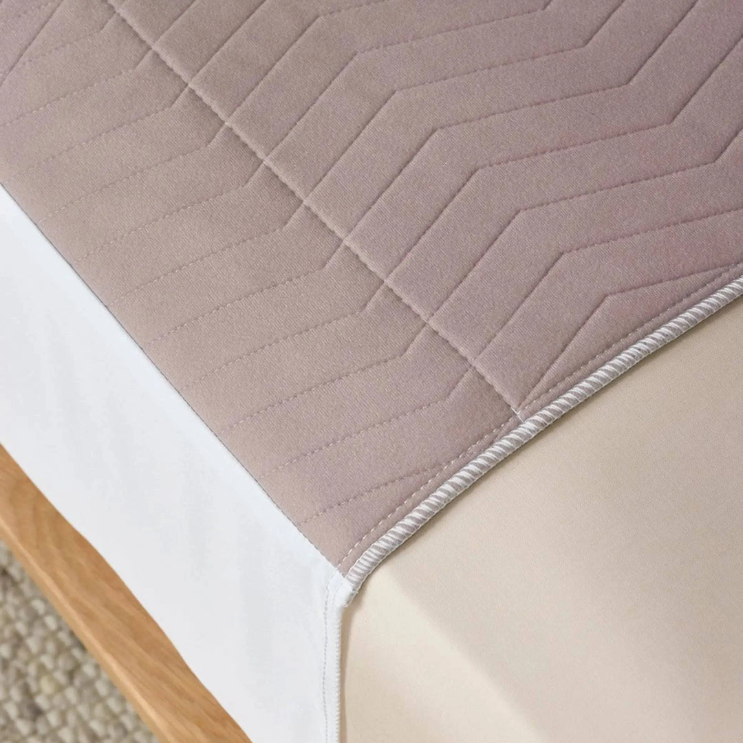 Close-up of the Clay Waterproof Bed Pad, referred to by some as Kylie bed pad in warm neutral tones, featuring a soft, quilted design for extra comfort. This reusable and washable bed pad provides incontinence protection with high absorbency and a waterproof backing to keep mattresses dry.
