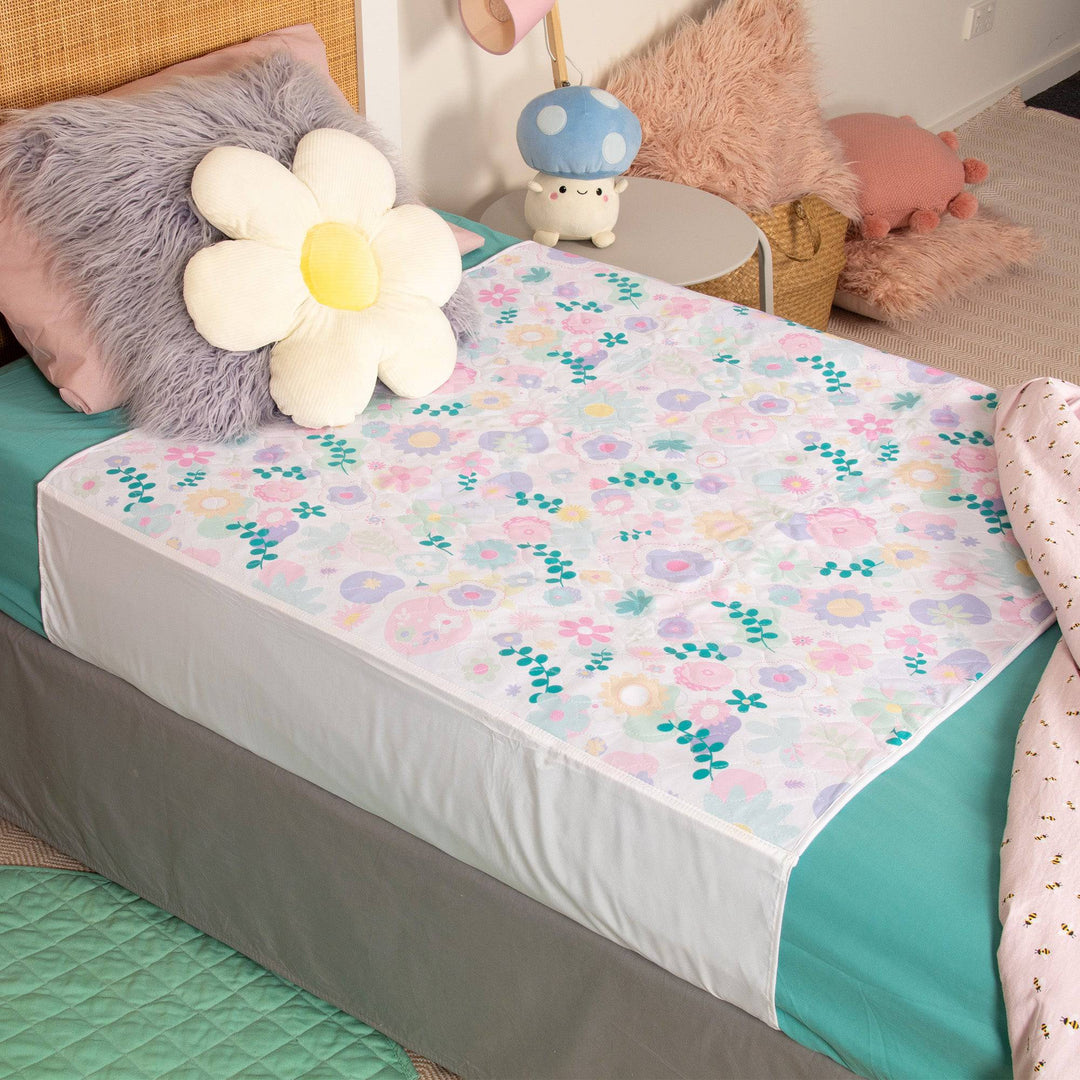 Conni kids bed pad with tuck-ins in a floral print, designed for added mattress protection and comfort for children.