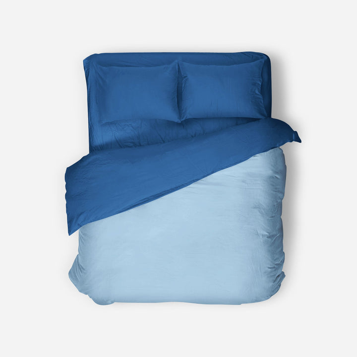 Blue bedding set with duvet and pillows on a white background
