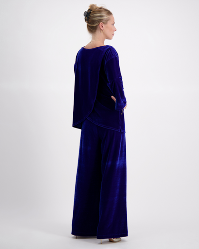 Jessie Wide Leg Velvet Pants shown in royal blue velvet from back view, paired with matching long-sleeve top, showcasing elegant flow and luxurious texture against white background. Side pockets visible, demonstrating practical design element.