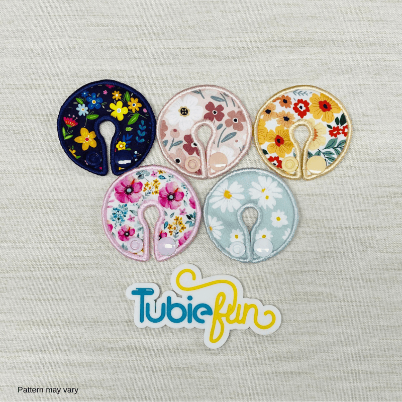 Five colorful flower-patterned G-tube button pads from Tubie Fun, designed for nutrition support and comfort.