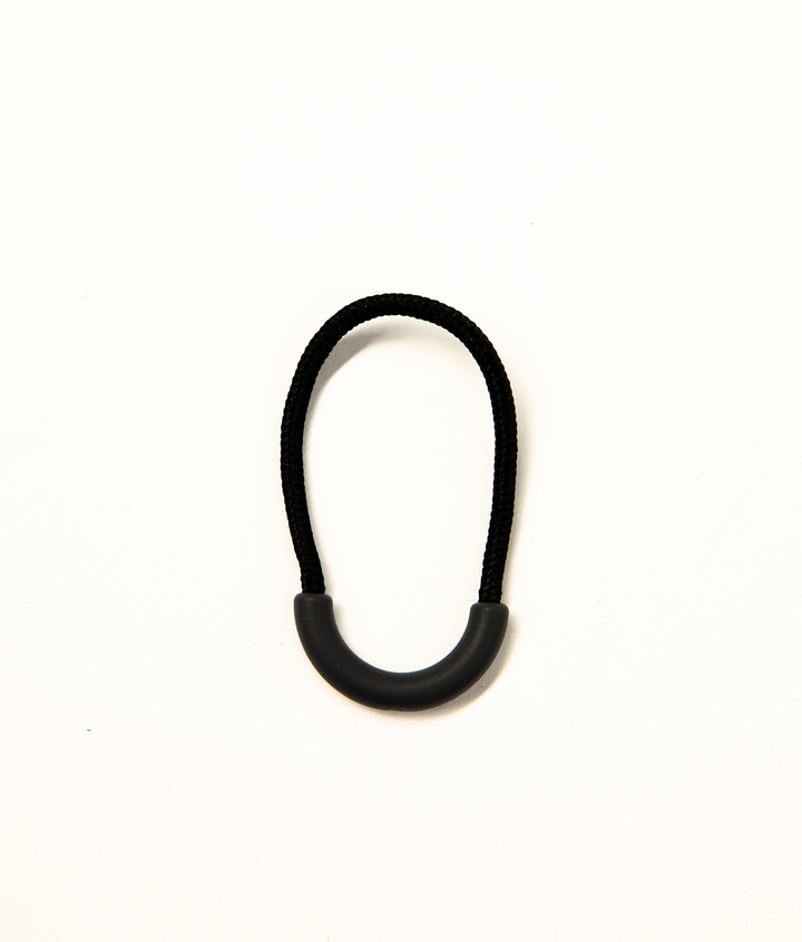 Black clothing zip puller from JAM the Label, featuring a sleek design and durable metal zipper for stylish, functional wear.