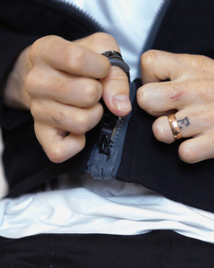Black ZIP puller from JAM the Label clothing line, featuring a sleek design and branded logo on the zipper tab.