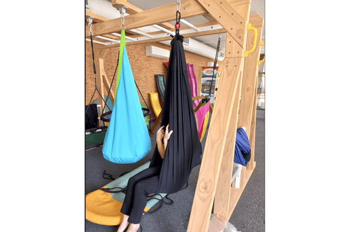 Black Lycra sensory swing for therapy, designed for play equipment by Special Needs Play Equipment, shown in use.