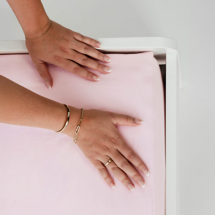 Two hands on a light pink surface with a neutral background