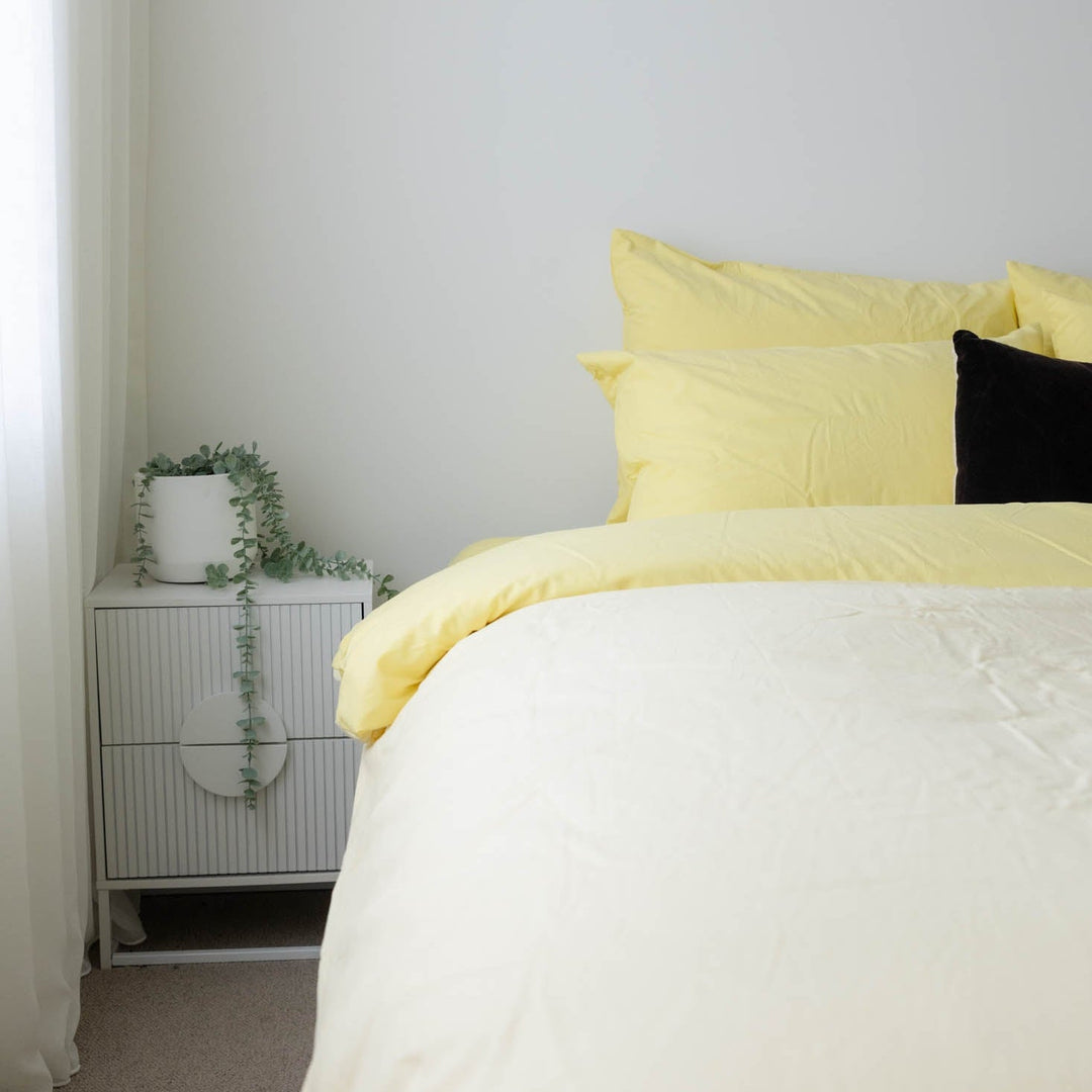 Bed with yellow bedding and a black pillow in a bedroom setting.