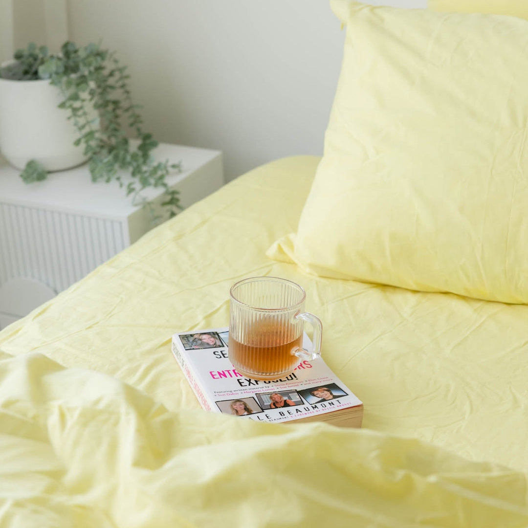 Yellow bedding with a glass of tea and magazine on a bed
