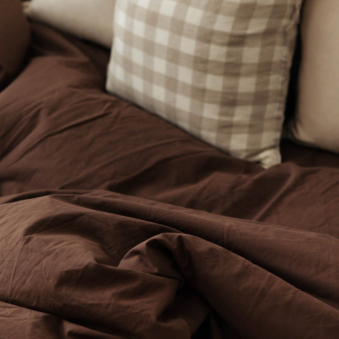Brown blanket draped over a sofa with checkered pillow