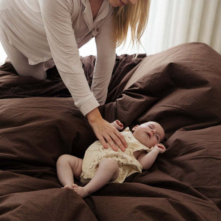 Woman interacting with a baby on a bed