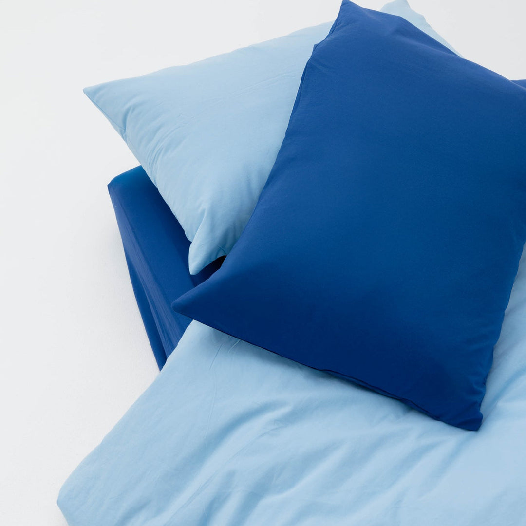 Blue and light blue pillows on a white surface
