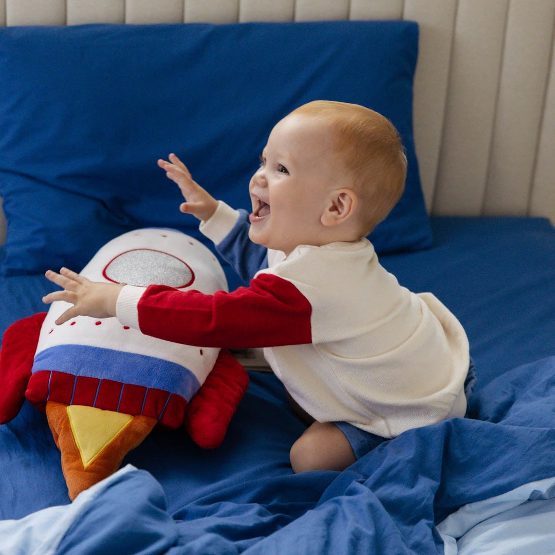 Baby playing with a plush toy on a bed