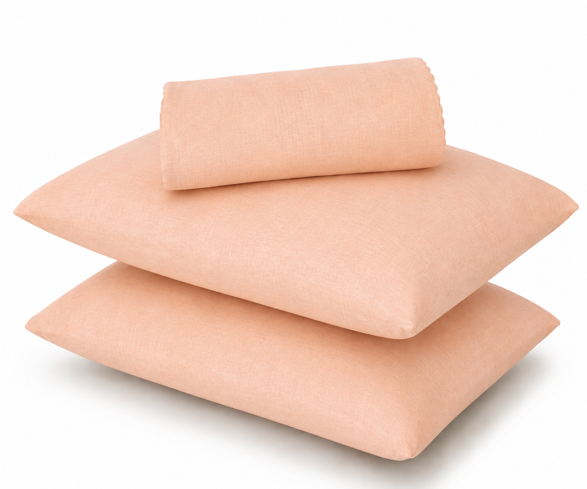 Three peach-colored pillowcases stacked on a white background, with one pillowcase folded over on top.