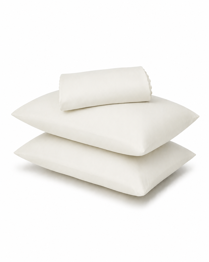 Three off-white pillows, including two flat square pillows and one rolled pillowcase, stacked on a white background.