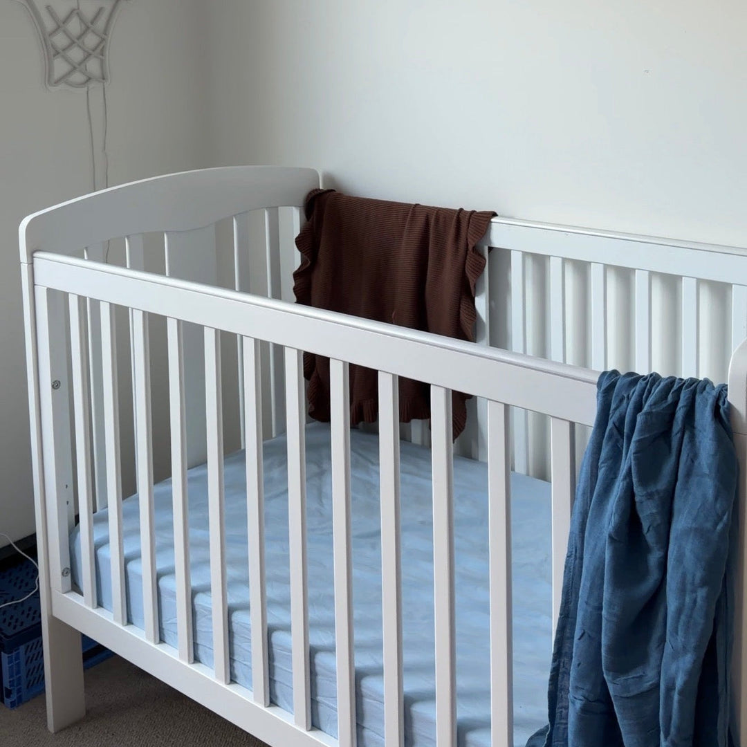 White crib in a room with a basketball hoop and star banner on the wall.