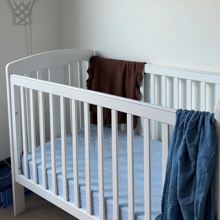 White crib in a room with a basketball hoop and star banner on the wall.