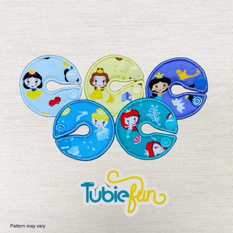 Five colorful G-tube button pads featuring princess designs from Tubie Fun for nutrition support.