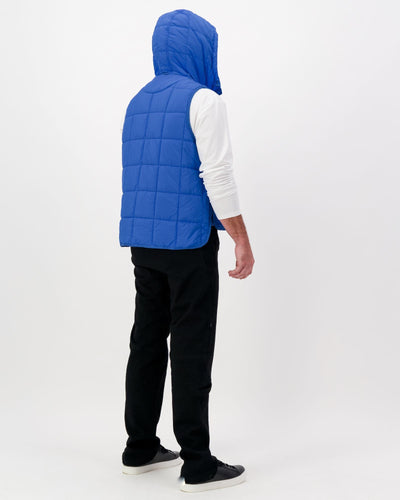 Standing male wearing a cobolt blue puffer vest over a white t-shirt and black pants. Christina Stephens Adaptive Clothing Australia.