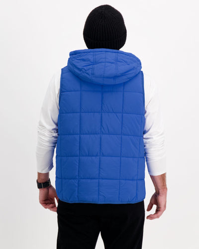 Standing male wearing a cobolt blue puffer vest over a white t-shirt and black pants. Christina Stephens Adaptive Clothing Australia.