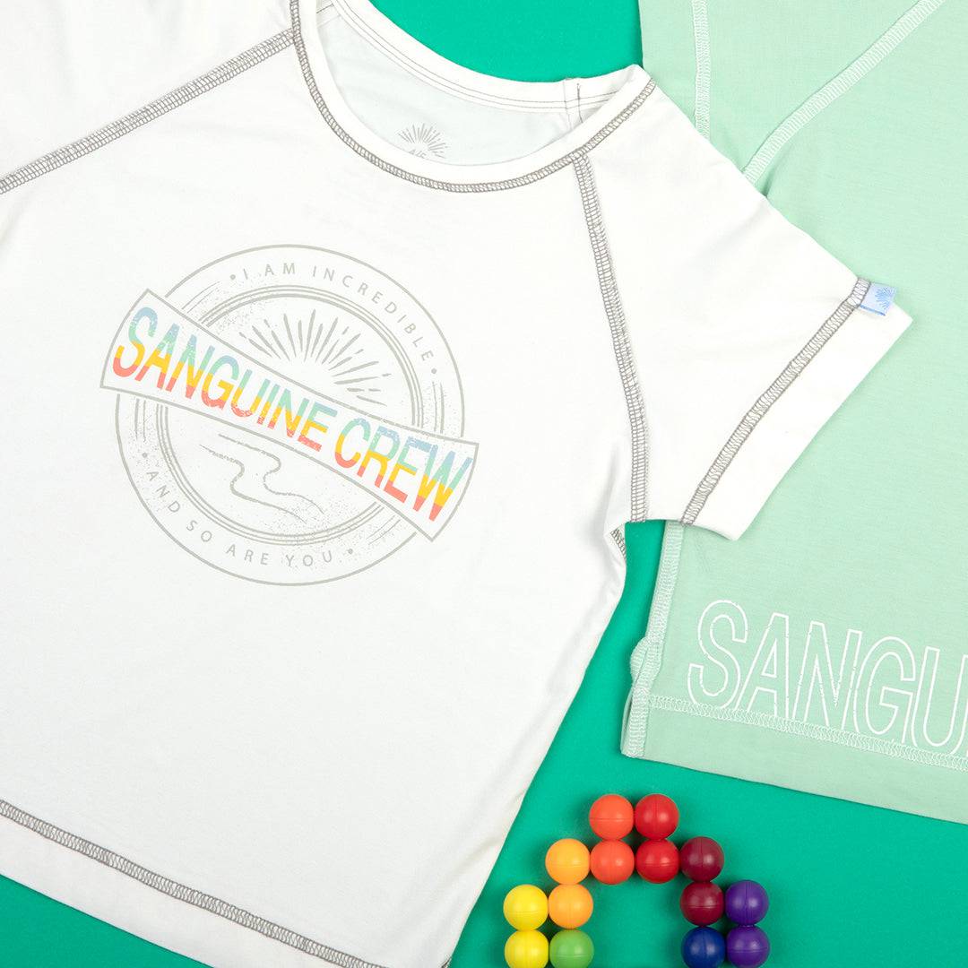 White Sanguine Crew kids bamboo short sleeve t-shirt displayed on a wooden surface, showcasing its soft fabric and simple design.