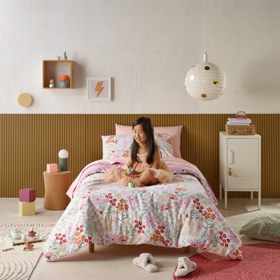 Girl playing on bed with floral waterproof bedding in pastel bedroom.