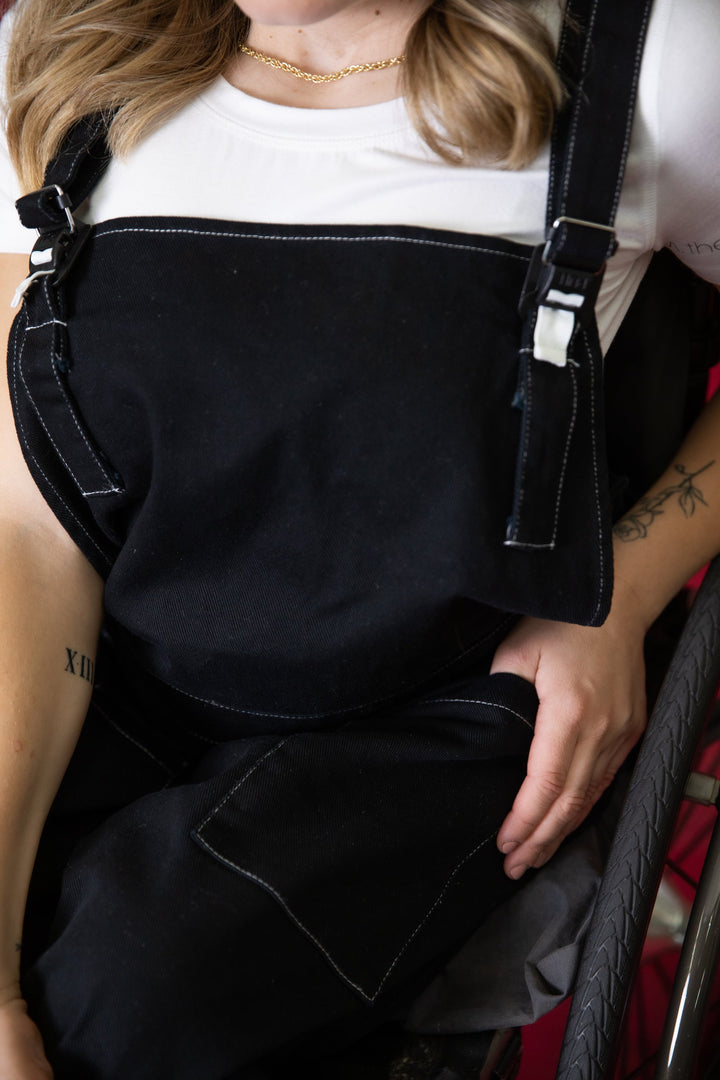 Close-up of JAM the Label magnetic buckle overalls showing a front pocket with detailed stitching and fabric texture.
