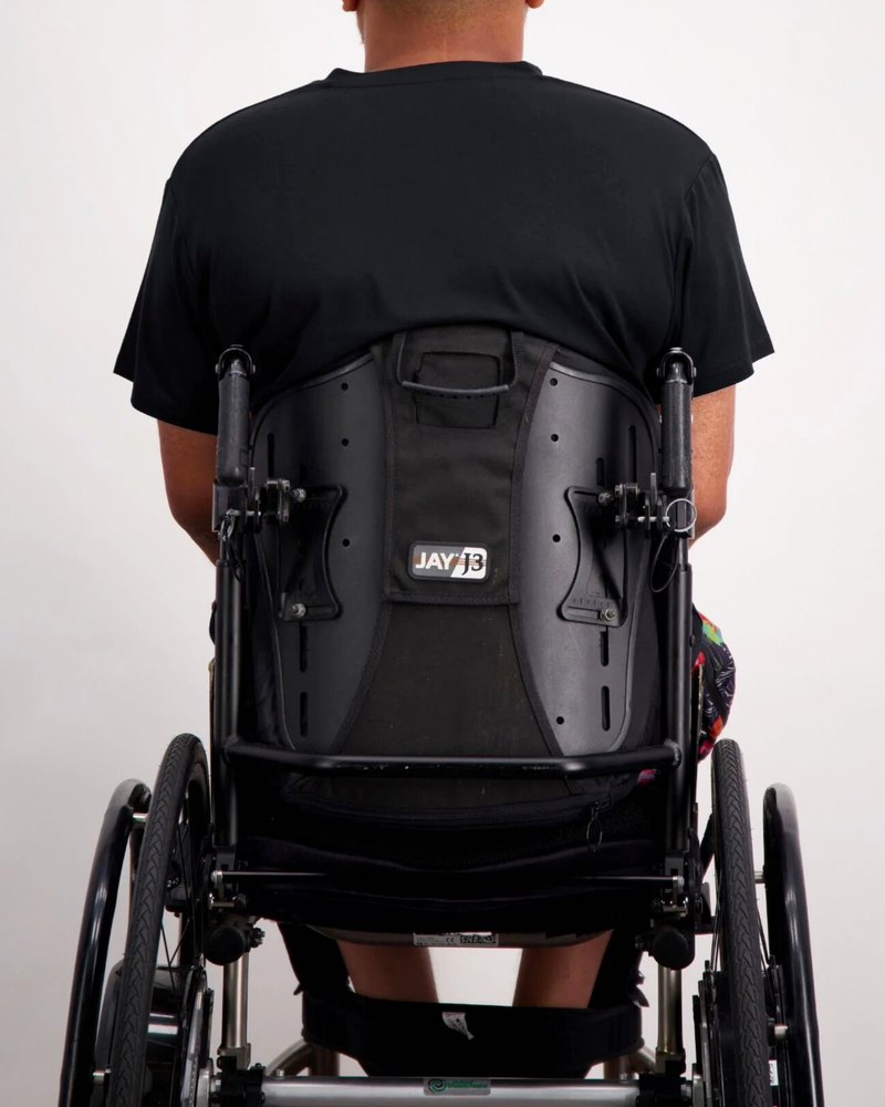 Nick A-Line Tee shown from behind on a wheelchair user, displaying the adaptive design with a clean black fabric against a white background. The shirt&