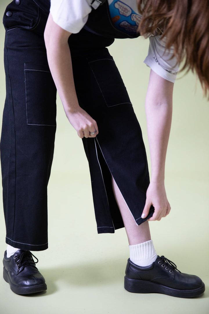 Close-up of JAM the Label magnetic buckle overalls showing calf zipper detail and denim fabric.