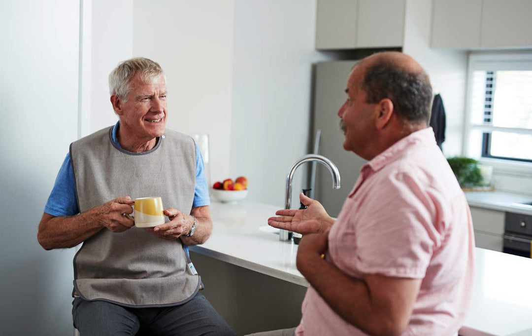 Adult washable tray bib from Brolly Sheets worn by a man, designed for adaptive clothing and easy cleaning.