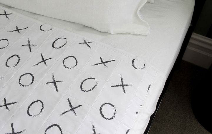 Brolly Sheets bed pad with wings in a hugs and kisses design, perfect for protecting bedding and ensuring comfort.