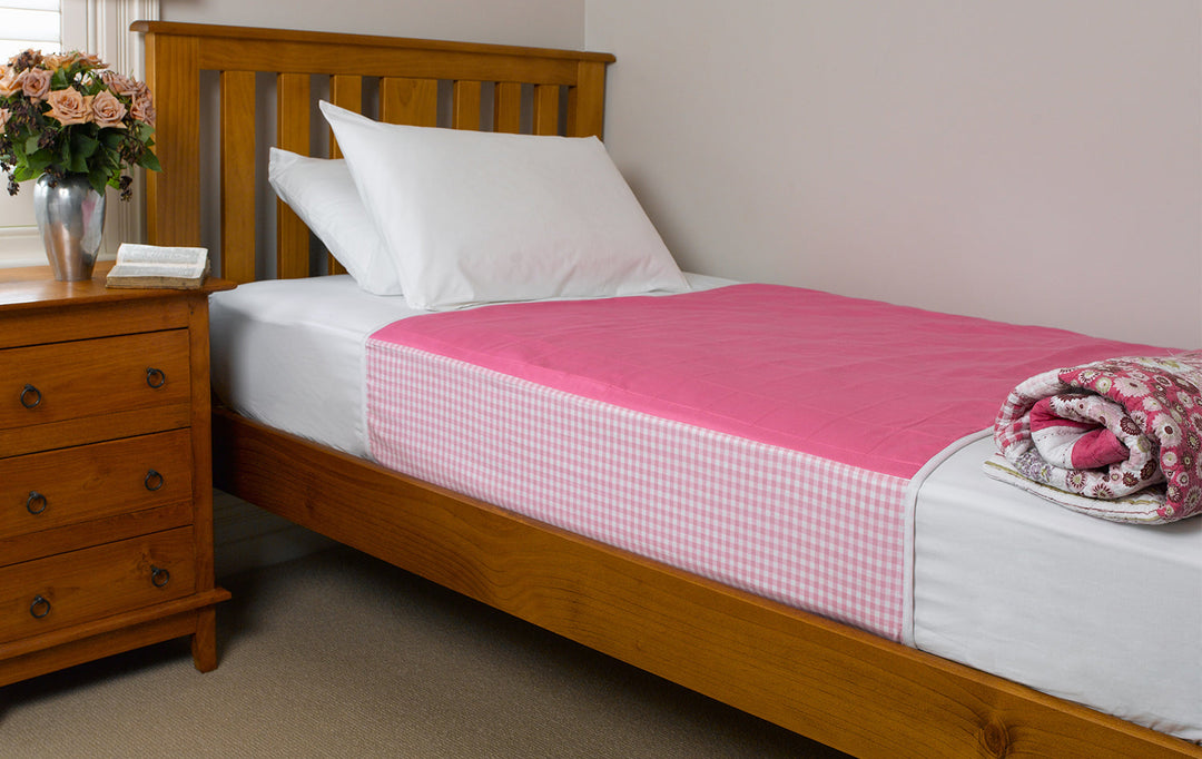 Brolly Sheets pink bed pad with wings for adults, designed to protect bedding and provide comfort during the night.