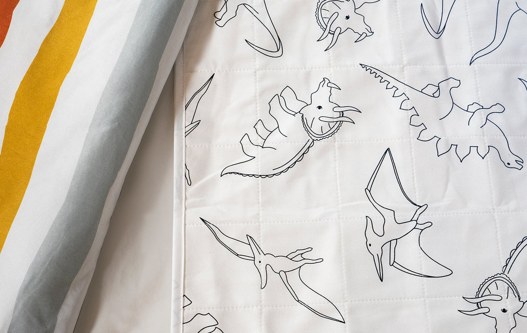 Brolly Sheets bed pad with wings featuring a colorful dinosaur print, designed for comfort and protection.