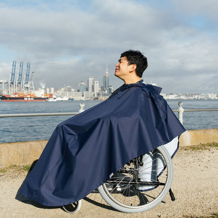 Side view of a Brolly Sheets Brolly Wheelchair Rain Coat designed for adaptive clothing, shown on a wheelchair user.