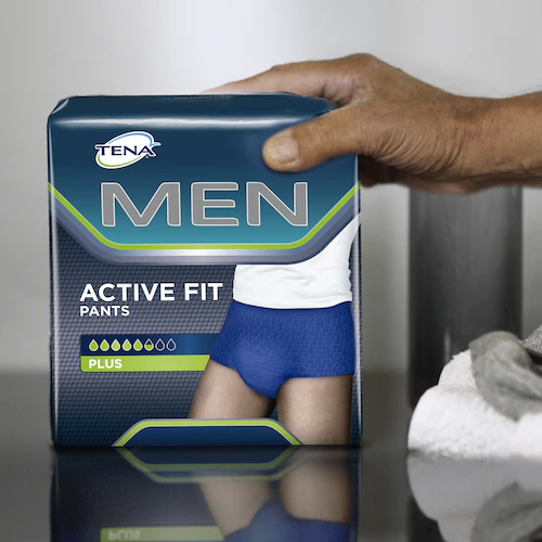 TENA Men Active Fit Pants Plus package held in hand, showcasing adult continence protection for men.